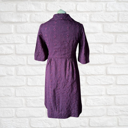 Purple dress with floral pattern on a white brick wall background