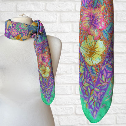 Colorful floral-patterned scarf on a mannequin against a white brick wall.