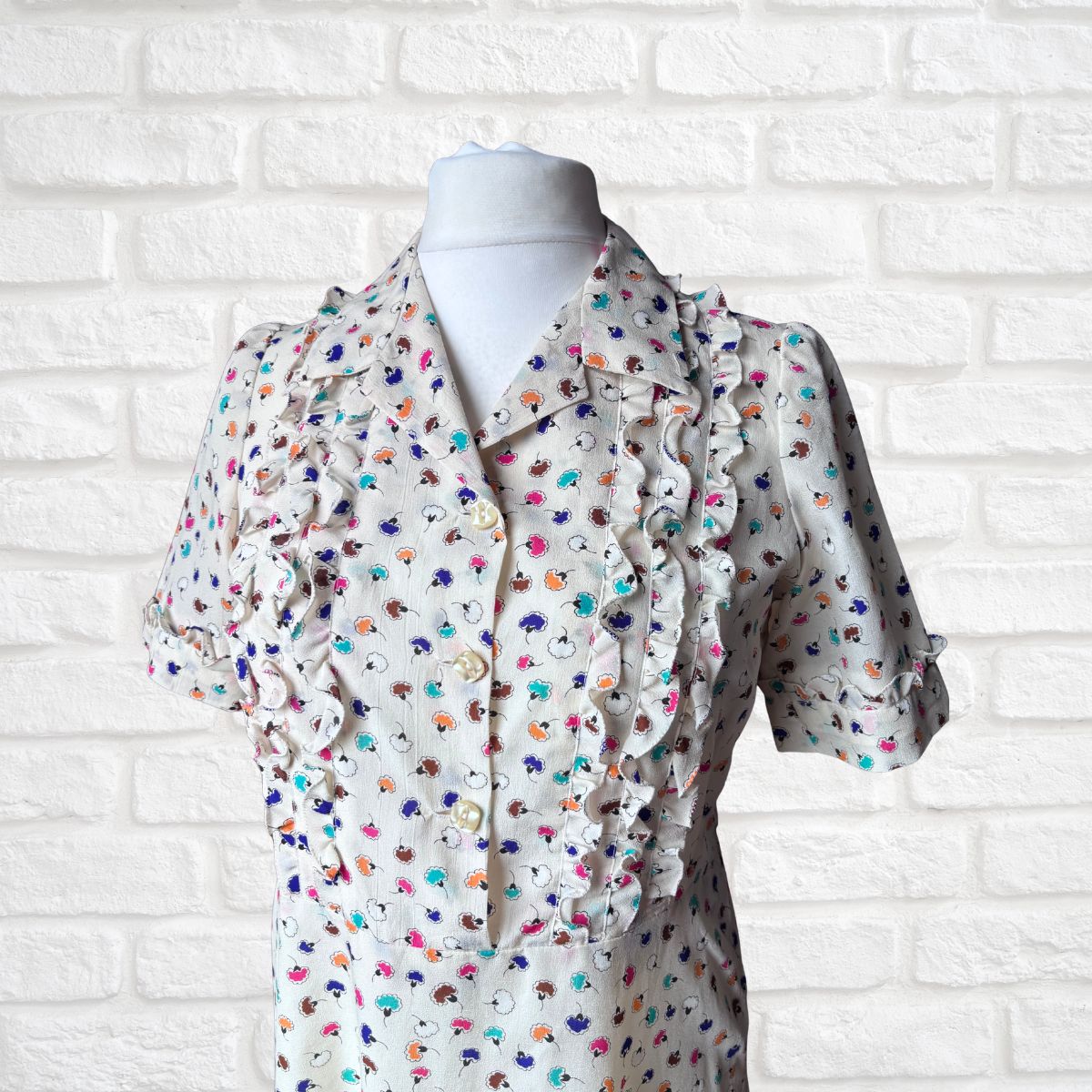 Mannequin wearing a floral dress against a white brick wall