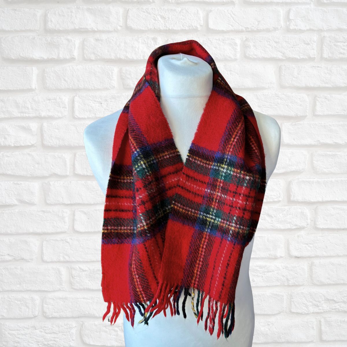 Red plaid scarf on a mannequin against a white brick wall background