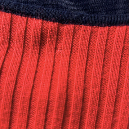 Close-up of a ribbed knit showing a bright red lower section and a dark navy ribbed cuff at the top.
