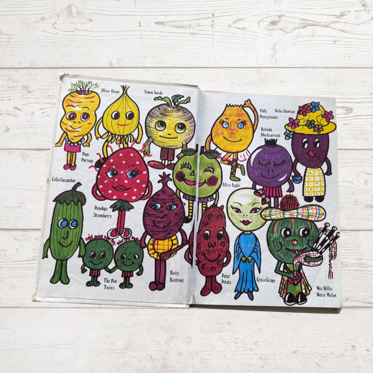 book open to pages with cartoon vegetable characters on a wooden suRface 