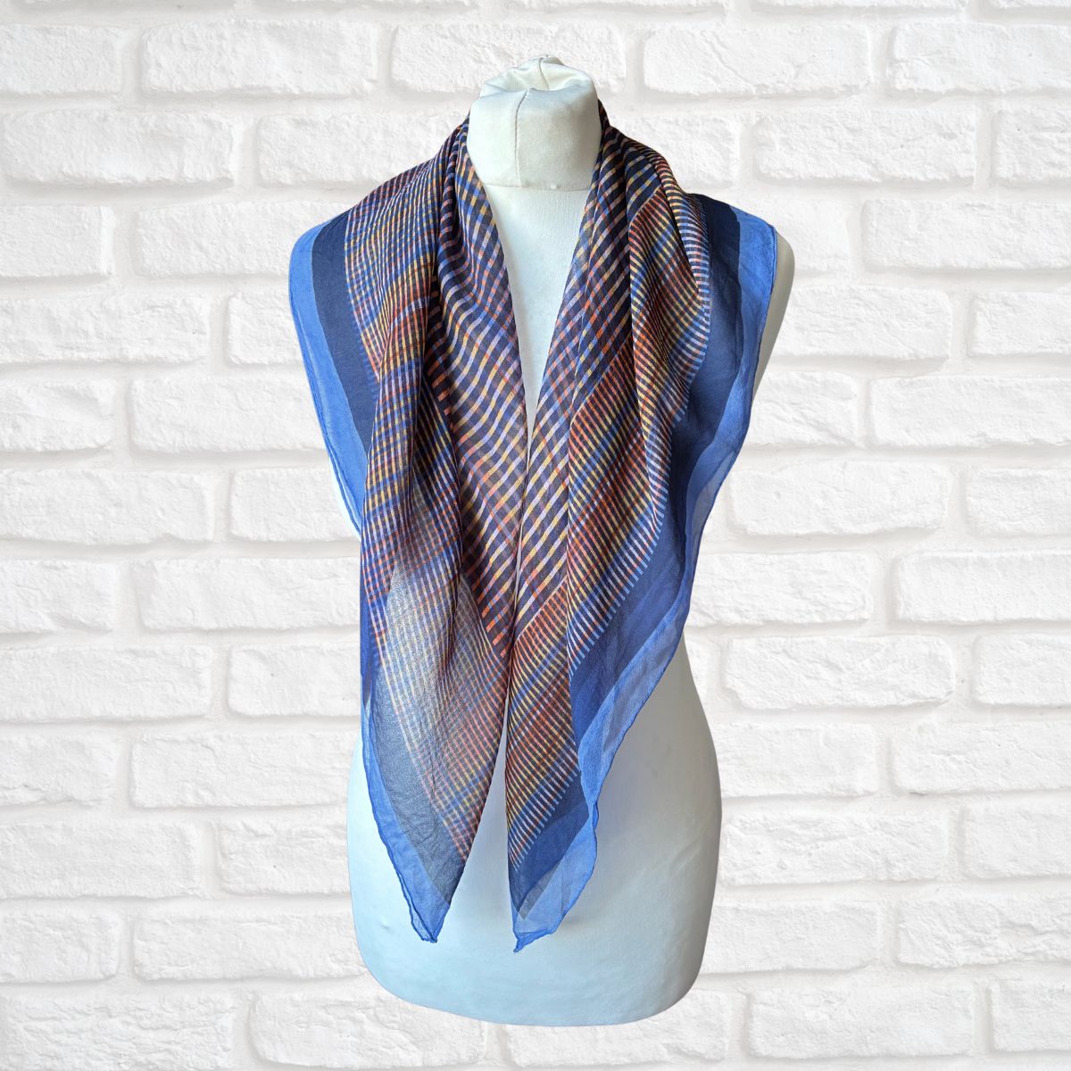 Geometric print scarf on a mannequin against a white brick wall background