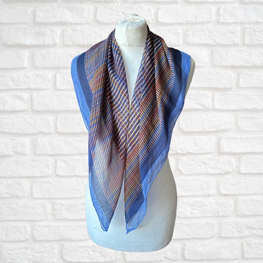 Geometric print scarf on a mannequin against a white brick wall background