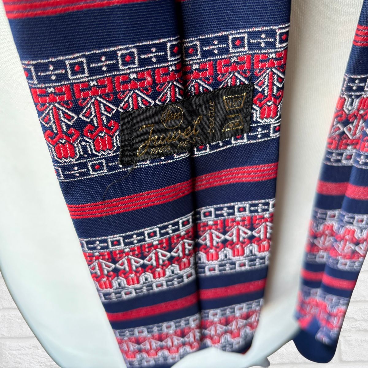 Navy and red patterned tie  with a brand label Juwel on a white background