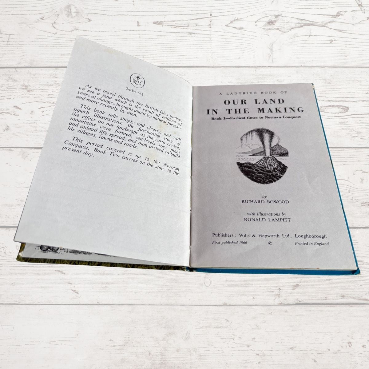 An open book titled 'Our Land in the Making' laid flat on a white wood surface, showing printed text and a small black-and-white illustration on the right page.