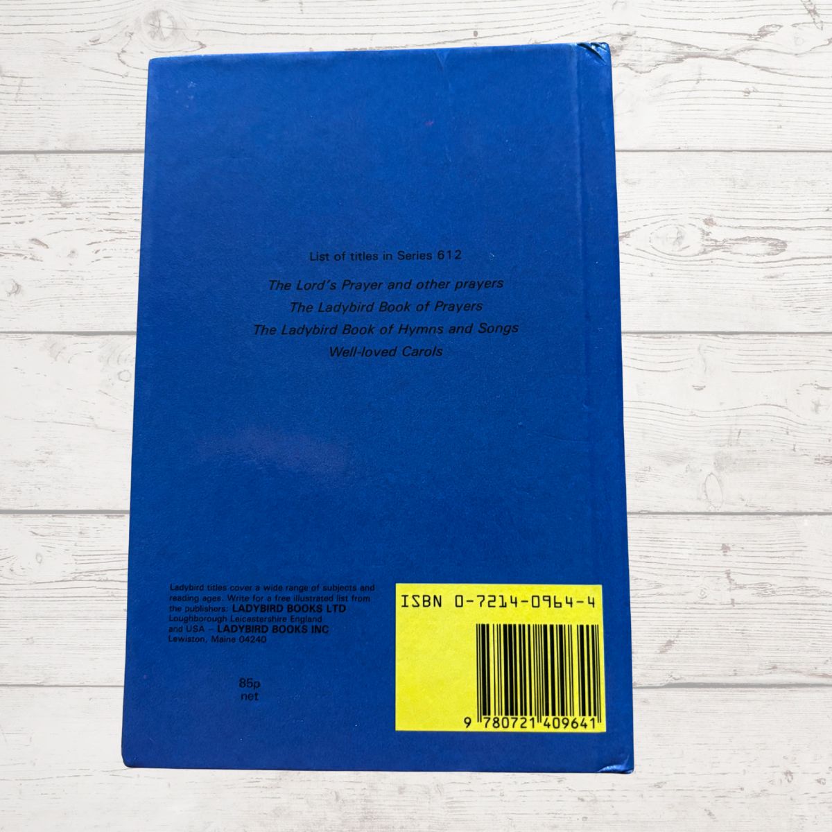 Blue book with a yellow label and barcode on a light wooden surface