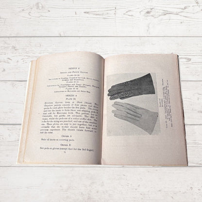 Open book with illustrations of gloves on a wooden surface