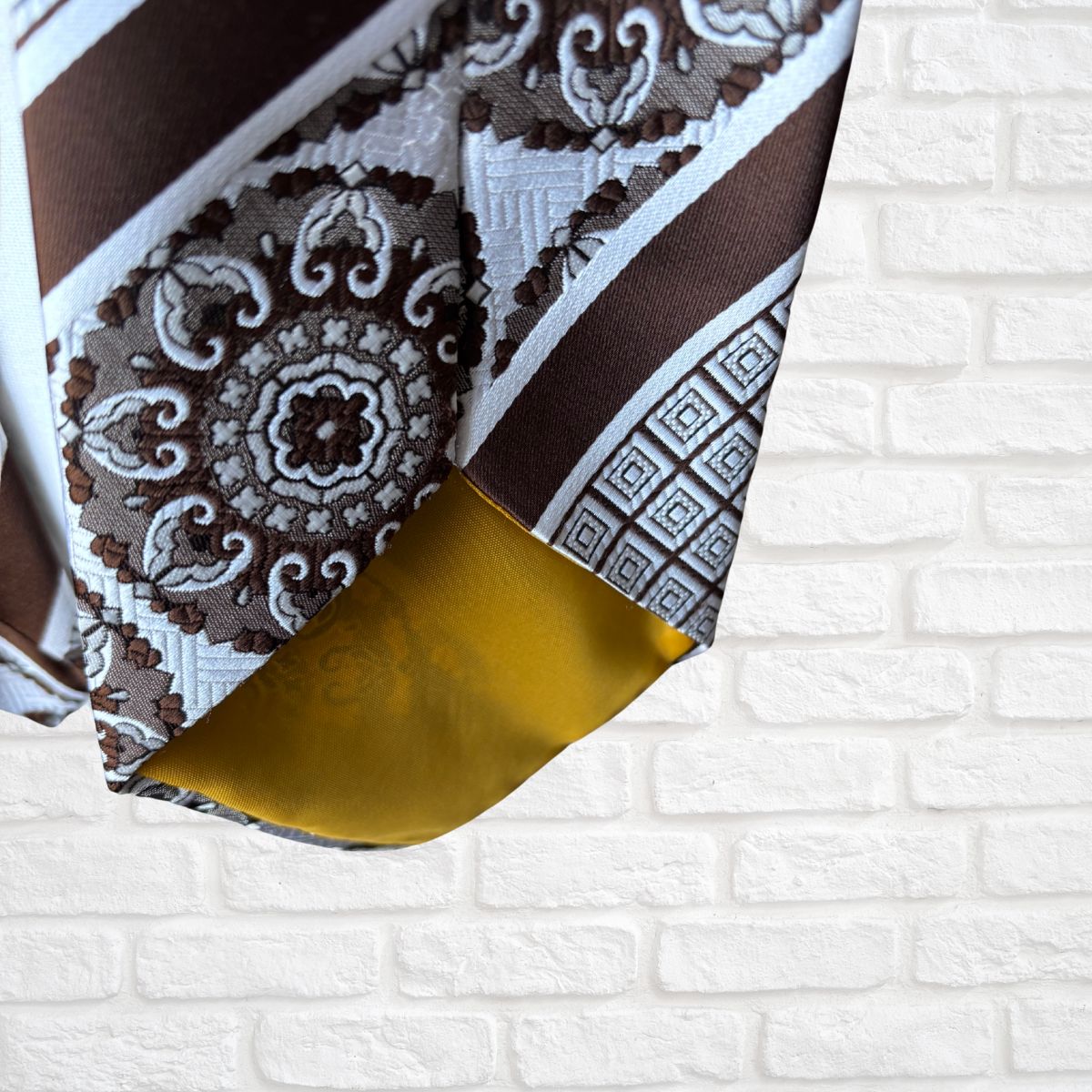 Patterned fabric with brown, white, and gold colors on a white brick background