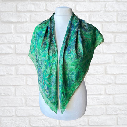 Green patterned scarf on a mannequin against a white brick wall background