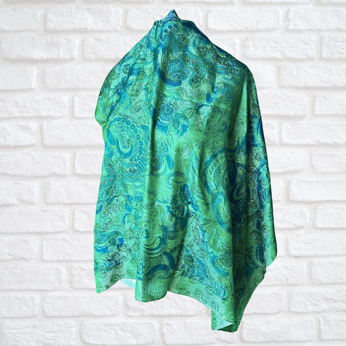 Green and blue patterned scarf on a white brick wall