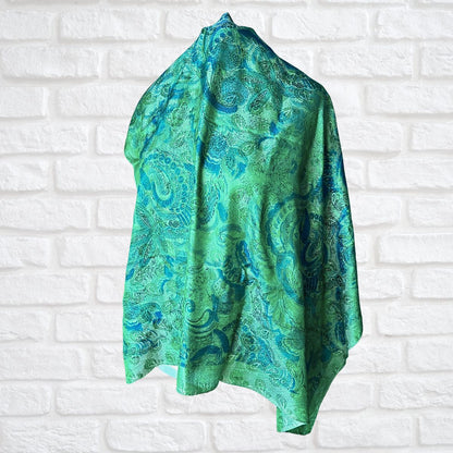 Green and blue patterned scarf on a white brick wall