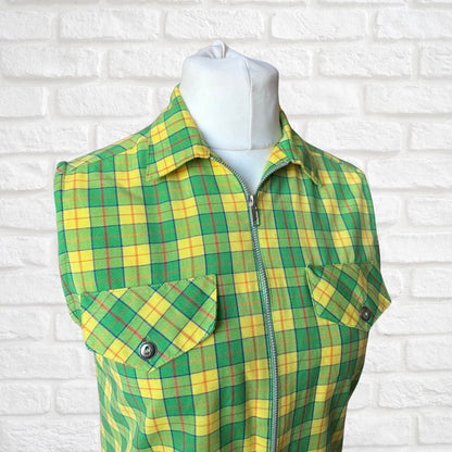 Green and yellow plaid shirt on a mannequin against a white brick wall.