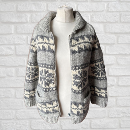 Knitted cardigan with a pattern on a mannequin against a white brick wall.