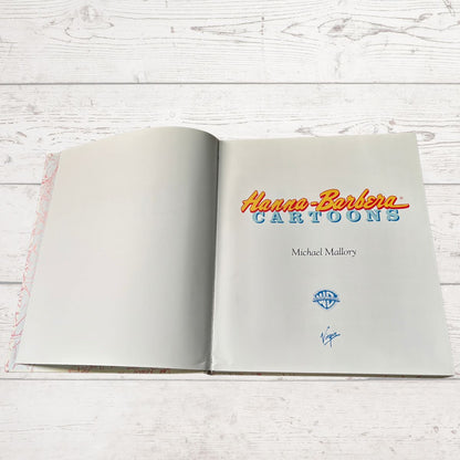 Open book with 'Hanna-Barbera Cartoons' title on a wooden surface