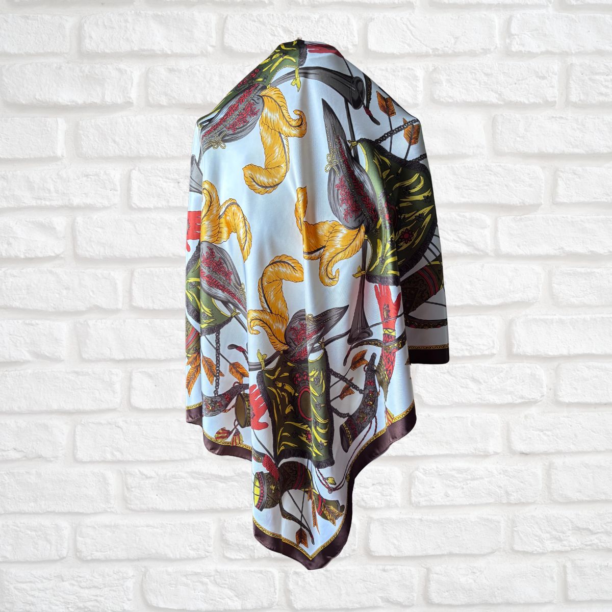 Colourful heraldic scarf with abstract design draped over a white brick wall