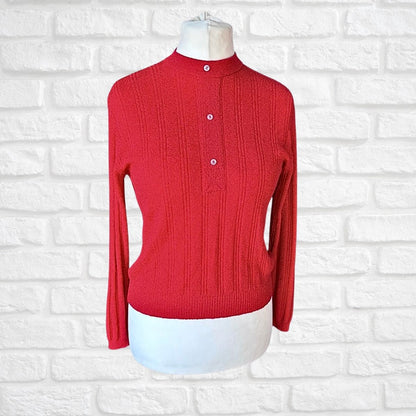 A red ribbed knit mock-neck sweater displayed on a white mannequin torso against a white brick wall background.
