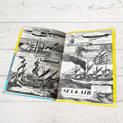 Open book with black and white illustrations of ships and airplanes on a wooden surface