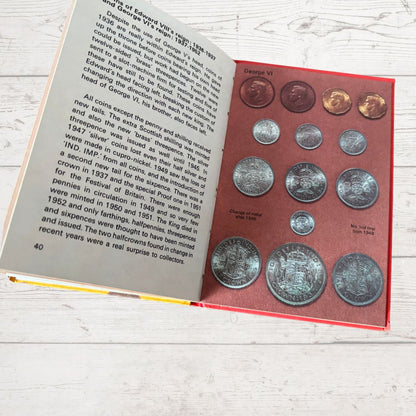 Collection of coins in a holder with an open book on a wooden surface