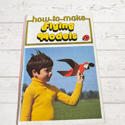 Book cover titled 'How to Make Flying Models' featuring a child with a model bird on a wooden surface.