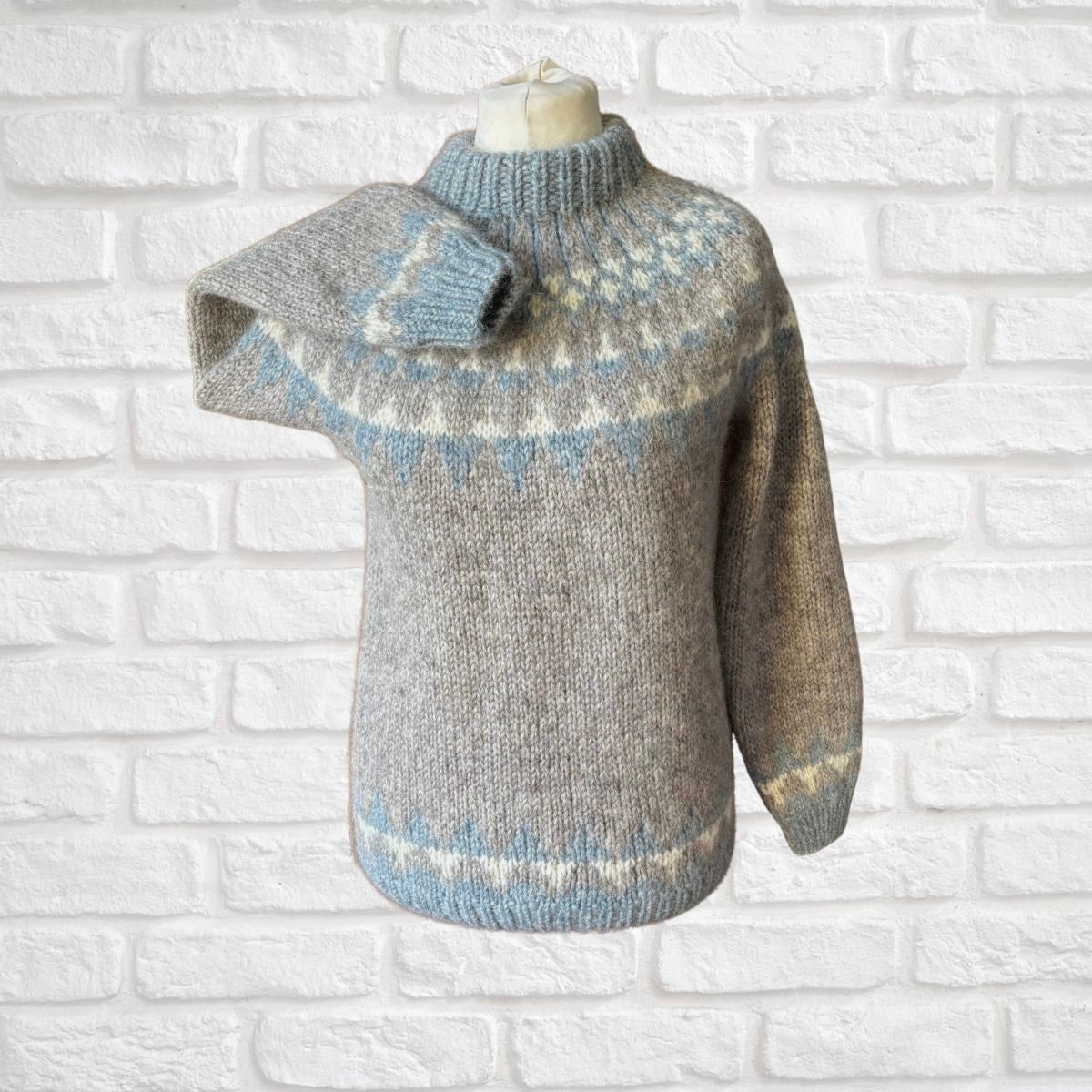 Knitted wool sweater with a pattern on a white brick wall background
