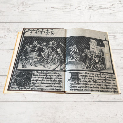 Open book with black and white illustrations on a light wooden surface