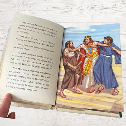 Open book with illustrated scene and text on a wooden surface