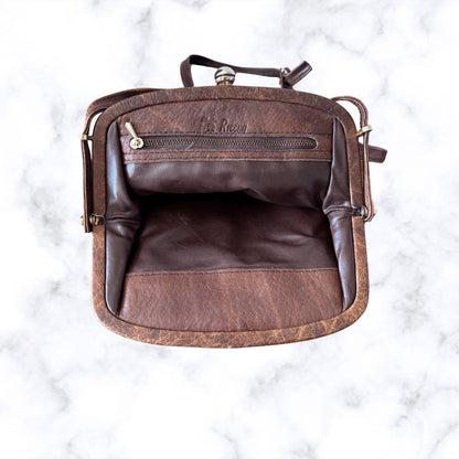 Brown leather look bag with visible branding on a white marble background