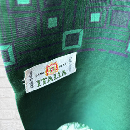 Close-up of a green patterned textile with a sewn white fabric label reading 'LANA SETA  ITALIA' 