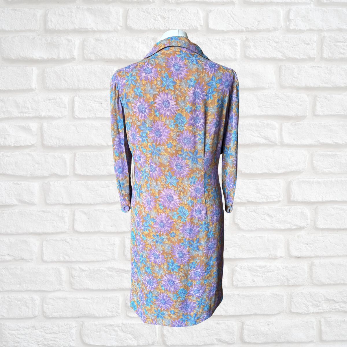 Floral dress on a mannequin against a white brick wall background