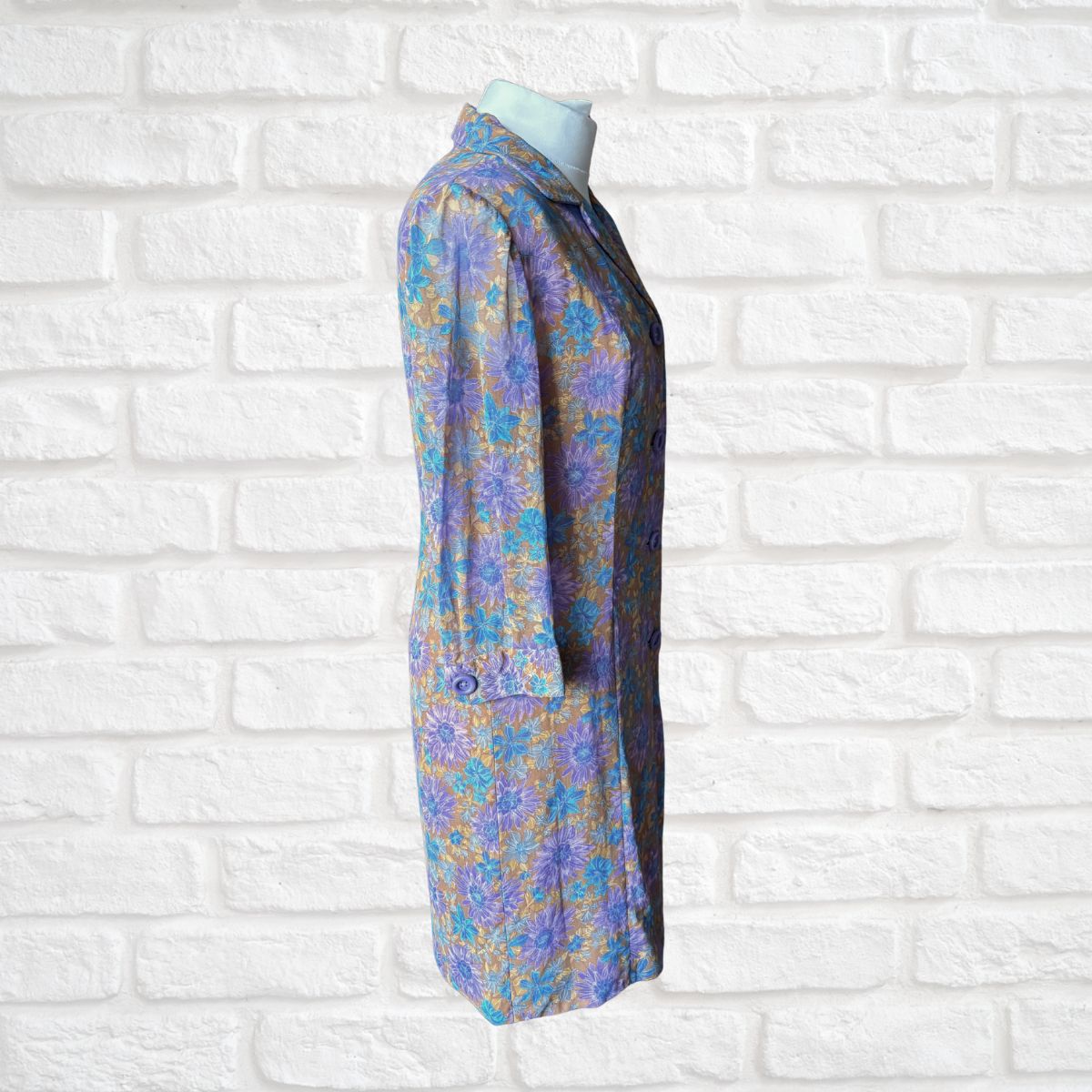 Floral-patterned dress on a mannequin against a white brick wall background