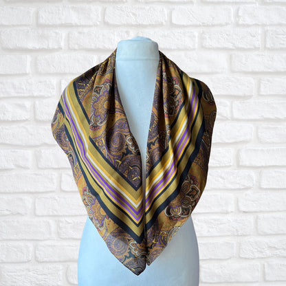 Patterned scarf on a mannequin against a white brick wall background