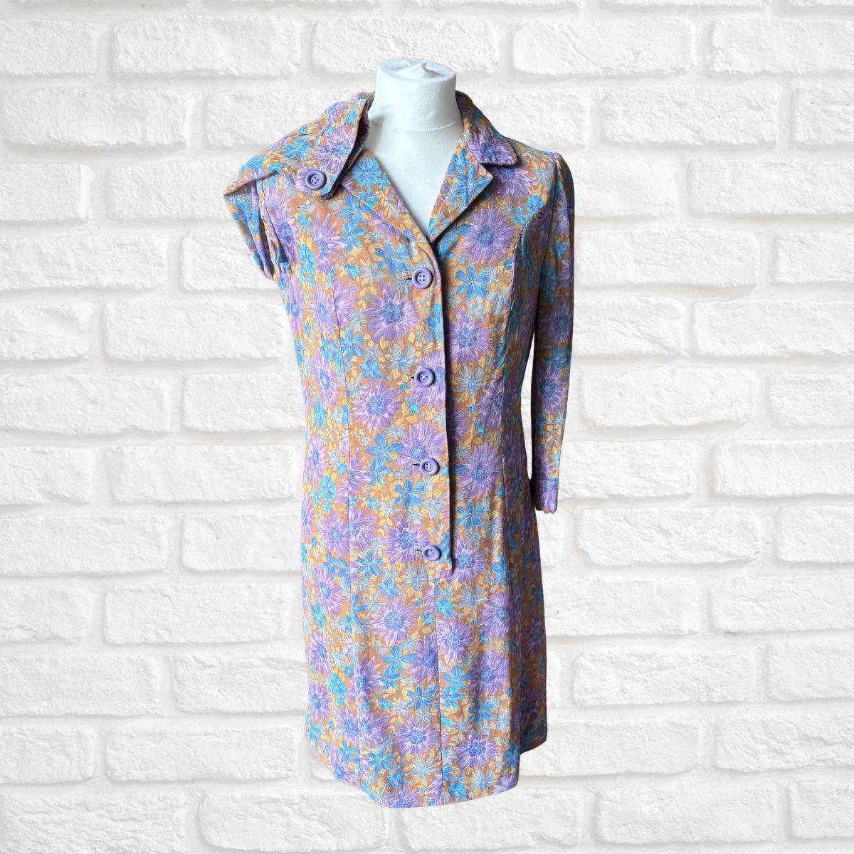 Floral patterned dress on a mannequin against a white brick wall background