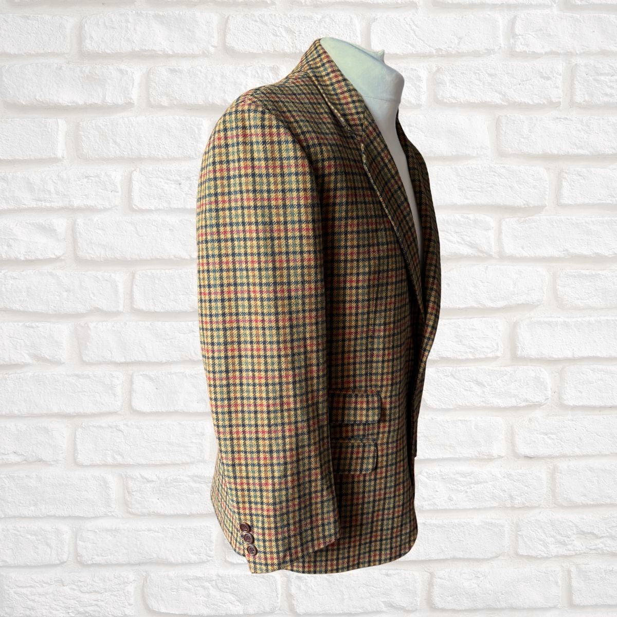 Plaid blazer on a mannequin against a white brick wall background