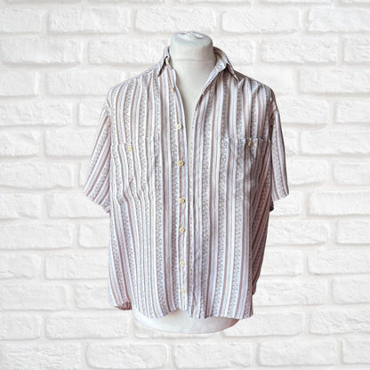 A short-sleeve button-up shirt with vertical stripes in beige, white, and light brown, displayed on a white mannequin torso against a white brick wall background.