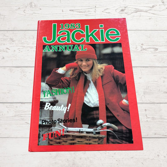 1983 Jackie Annual book cover with a woman in a red coat and hat on a light wooden surface