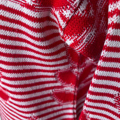 Close-up of a red and white knit fabric with horizontal stripes and a textured geometric pattern.