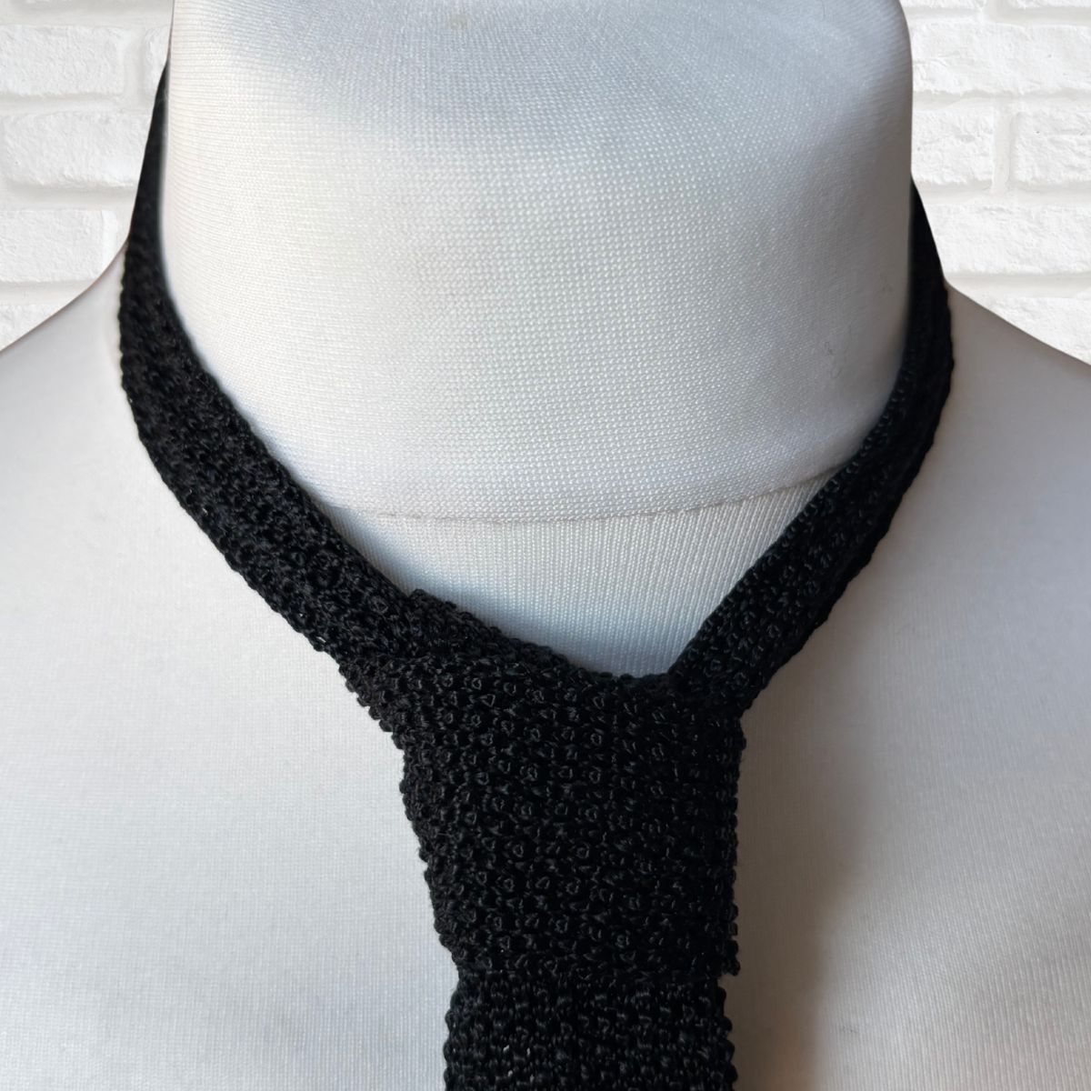 Black knitted tie on a mannequin with a white background