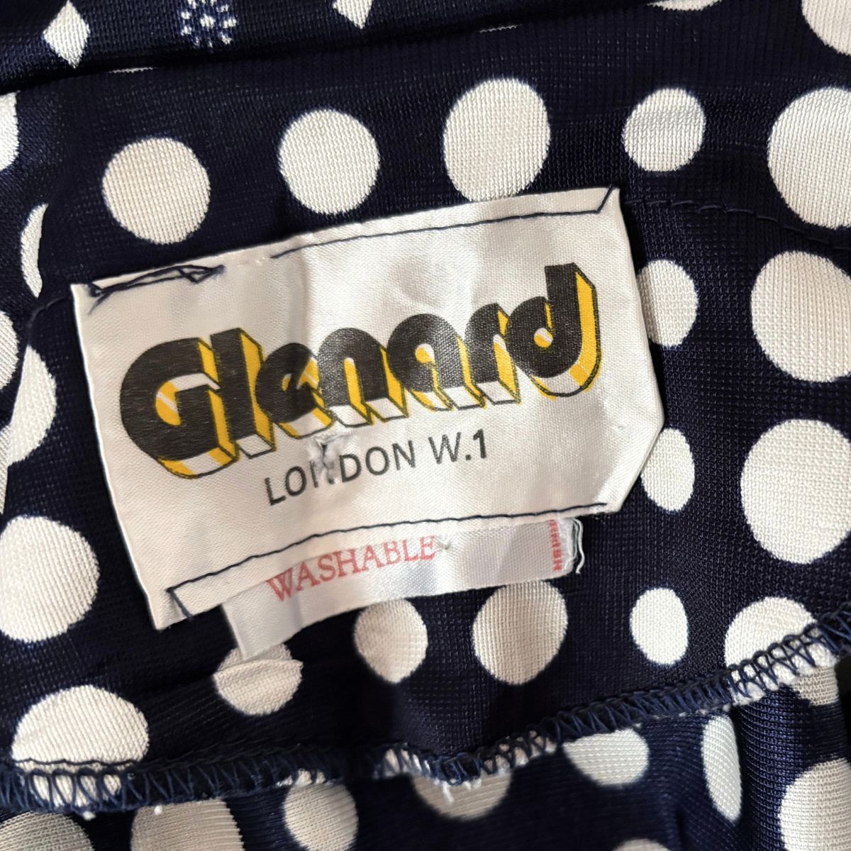 Label with 'Glenard London W.1' on a polka dot fabric background