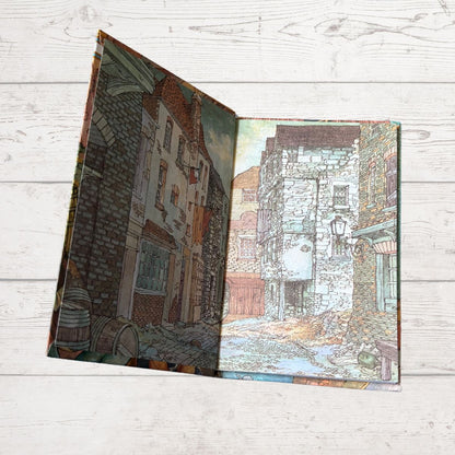 Open book showing a detailed illustration of an old town street on a wooden surface