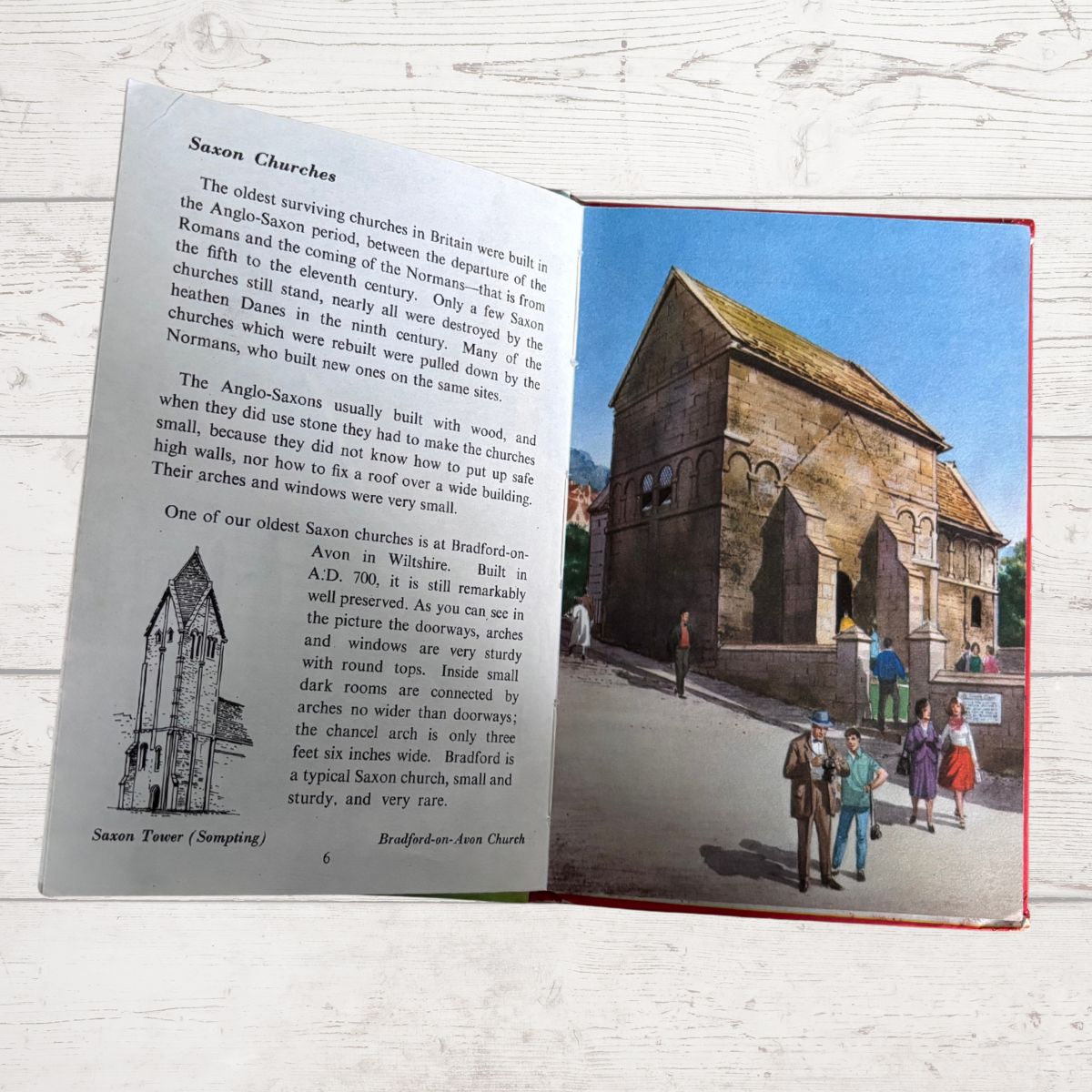 An open printed booklet or book spread laid on a white wood surface, showing text about Saxon churches and a large historical church illustration on the right page.