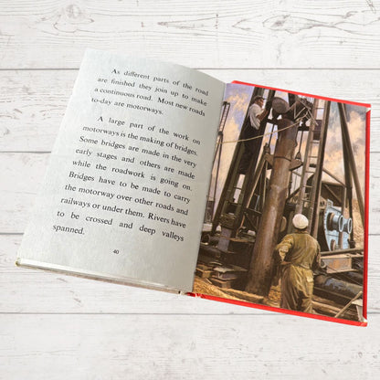 Open book with text and vintage illustration of construction workers on a wooden surface