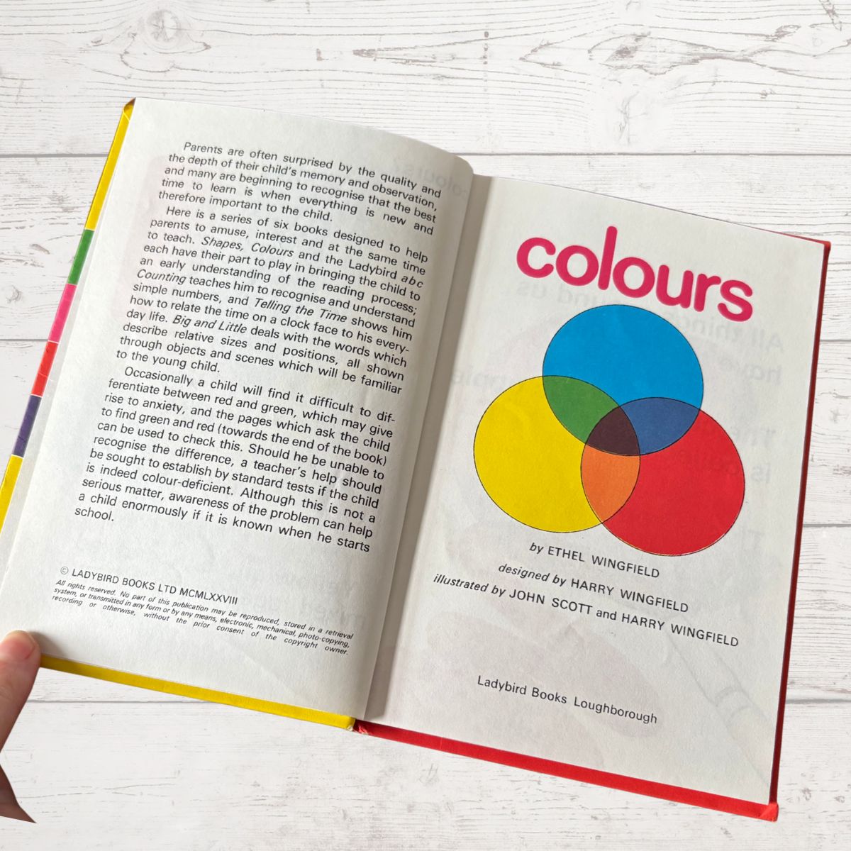 Open book titled 'colours' with a Venn diagram illustration on a white wooden surface.