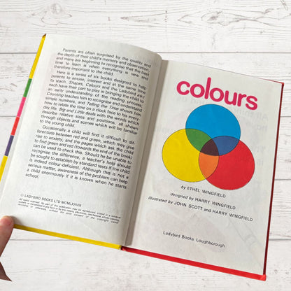 Open book titled 'colours' with a Venn diagram illustration on a white wooden surface.