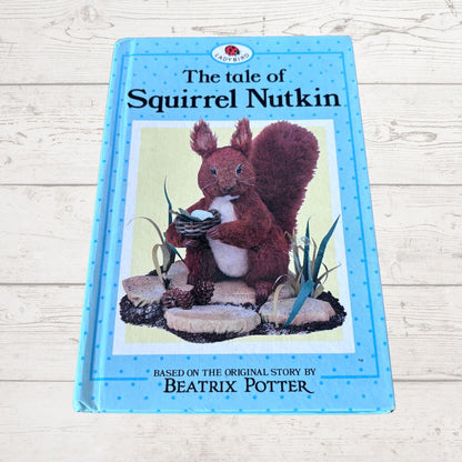 Book titled 'The Tale of Squirrel Nutkin' by Beatrix Potter on a wooden surface
