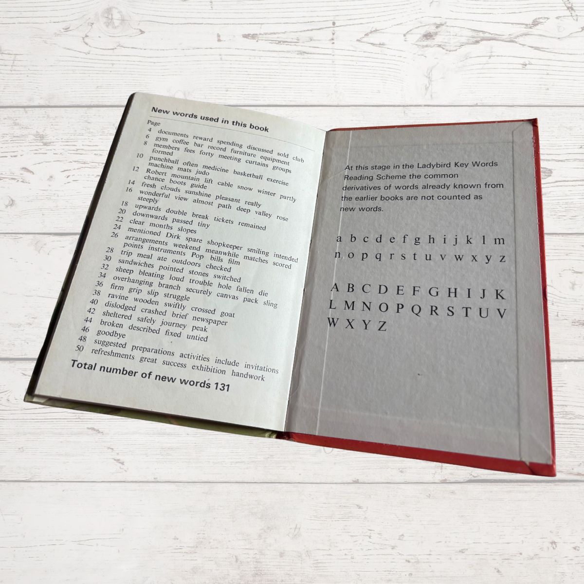 Open book with text and alphabet on a light wooden surface
