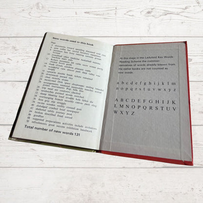Open book with text and alphabet on a light wooden surface