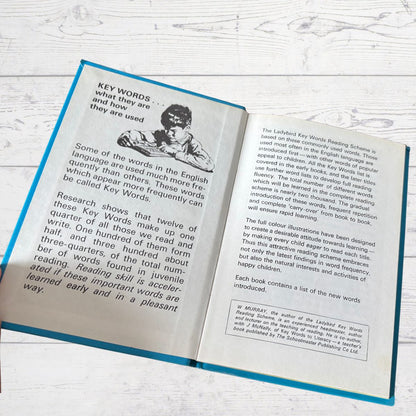 Open book with text and illustrations on a wooden surface