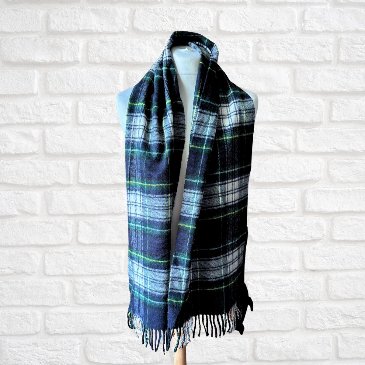 Plaid scarf on a mannequin against a white brick wall background