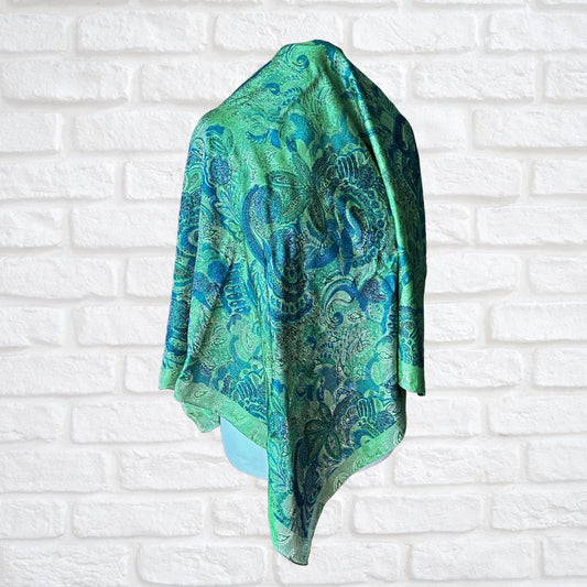 Green and blue patterned scarf draped over a white brick wall